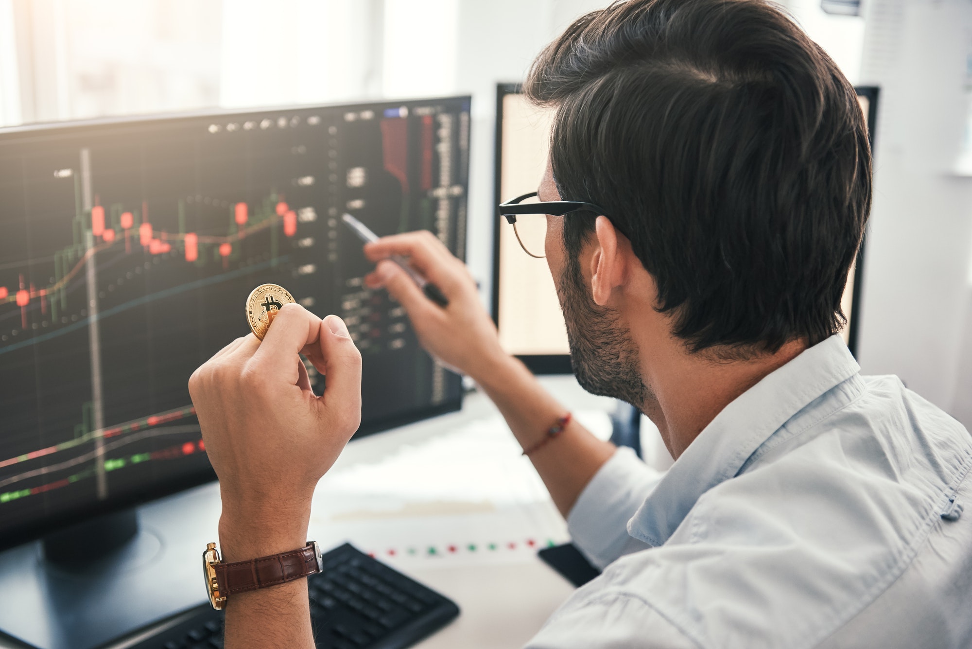 Exchange stock market. Back view of young professional trader in eyeglasses pointing on the data on