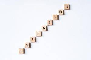 INFLATION spelled out using wooden letter tiles going up direction on white surface background.