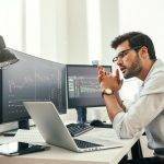 Trading strategy. Successful young trader in eyeglasses looking at analyzing trading charts on
